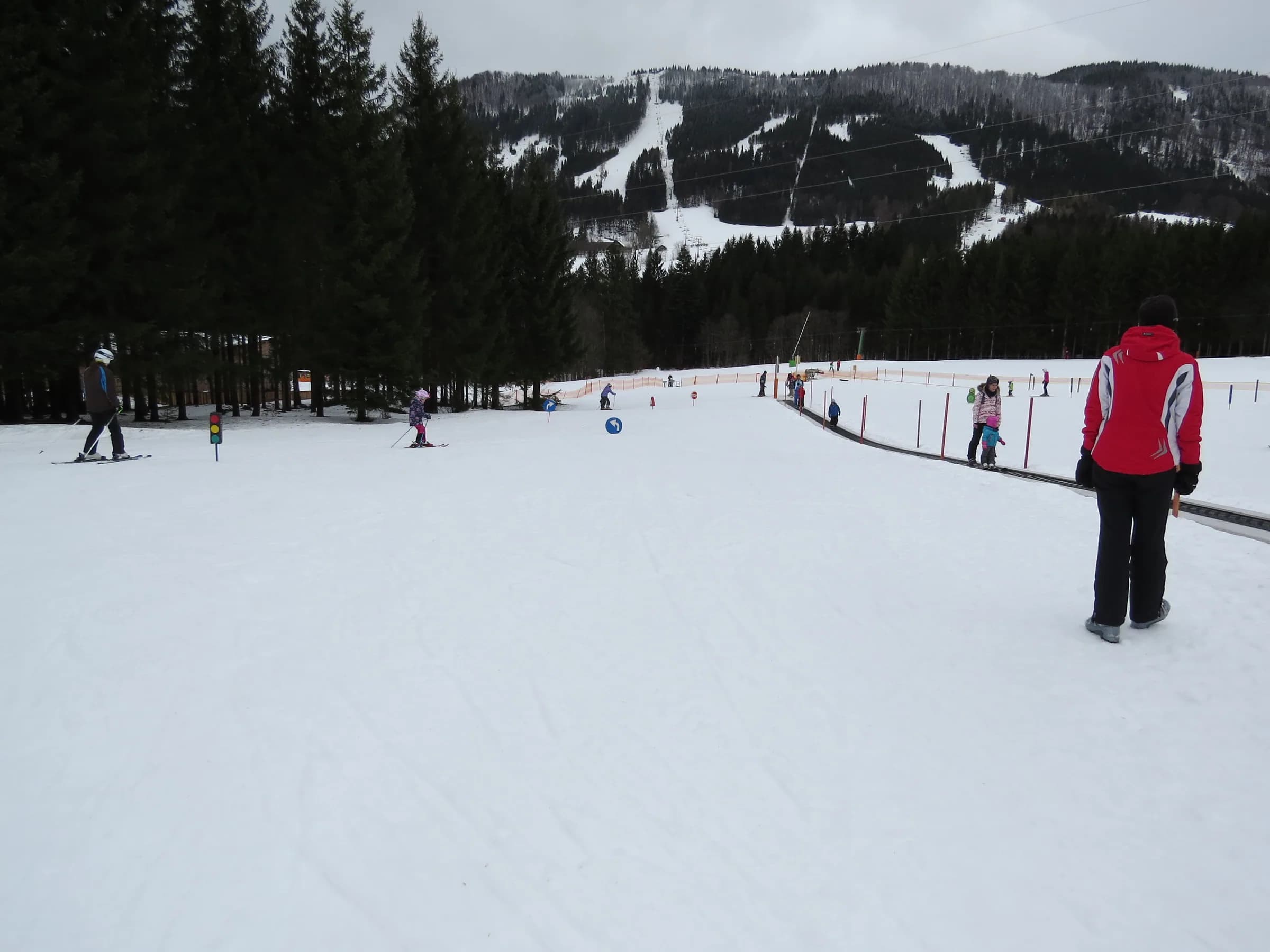 Skifahrende im Anna-Land mit Förderband und verschneiten Hängen im Hintergrund