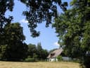 Gsängerhütte hinter einer Wiese, eingerahmt von Bäumen im Naturpark Eichenhain