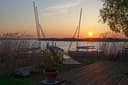 Sonnenaufgang am Neusiedler See bei Rust mit Holzsteg, Schilf und Bootsmasten