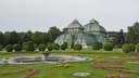 Palmenhaus Schönbrunn hinter Rasenflächen und farbigen Blumenbeeten