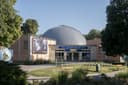 Kuppel und gläserner Eingang des Planetariums Wien zwischen Bäumen