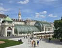 Palmenhaus im Wiener Burggarten mit geschwungener Glasfassade und belebter Terrasse
