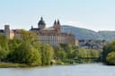 Stift Melk mit gelber Fassade und zwei Kirchtürmen über dem bewaldeten Donauufer
