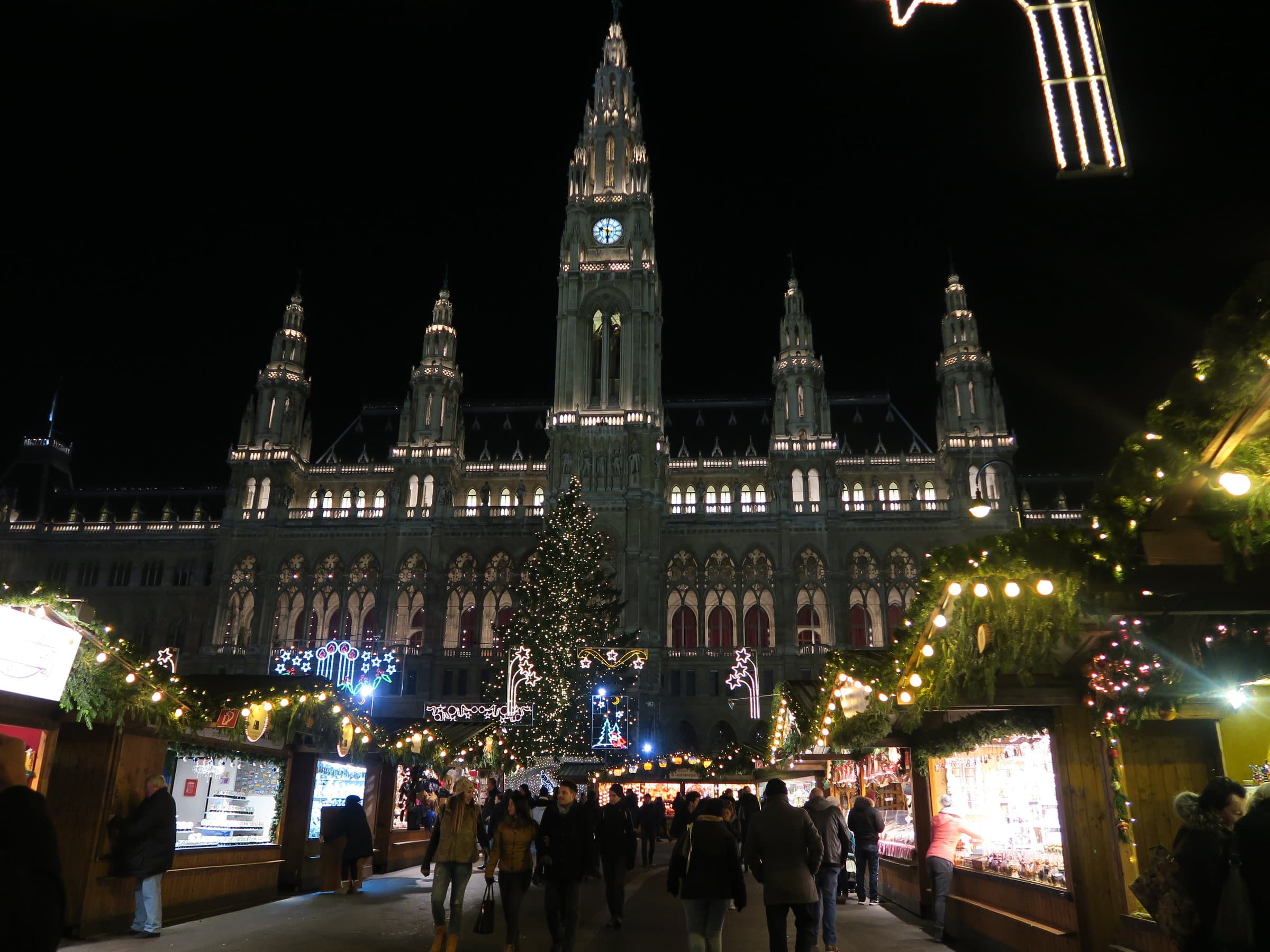 Beleuchtetes Wiener Rathaus mit Christbaum und Marktständen am Rathausplatz