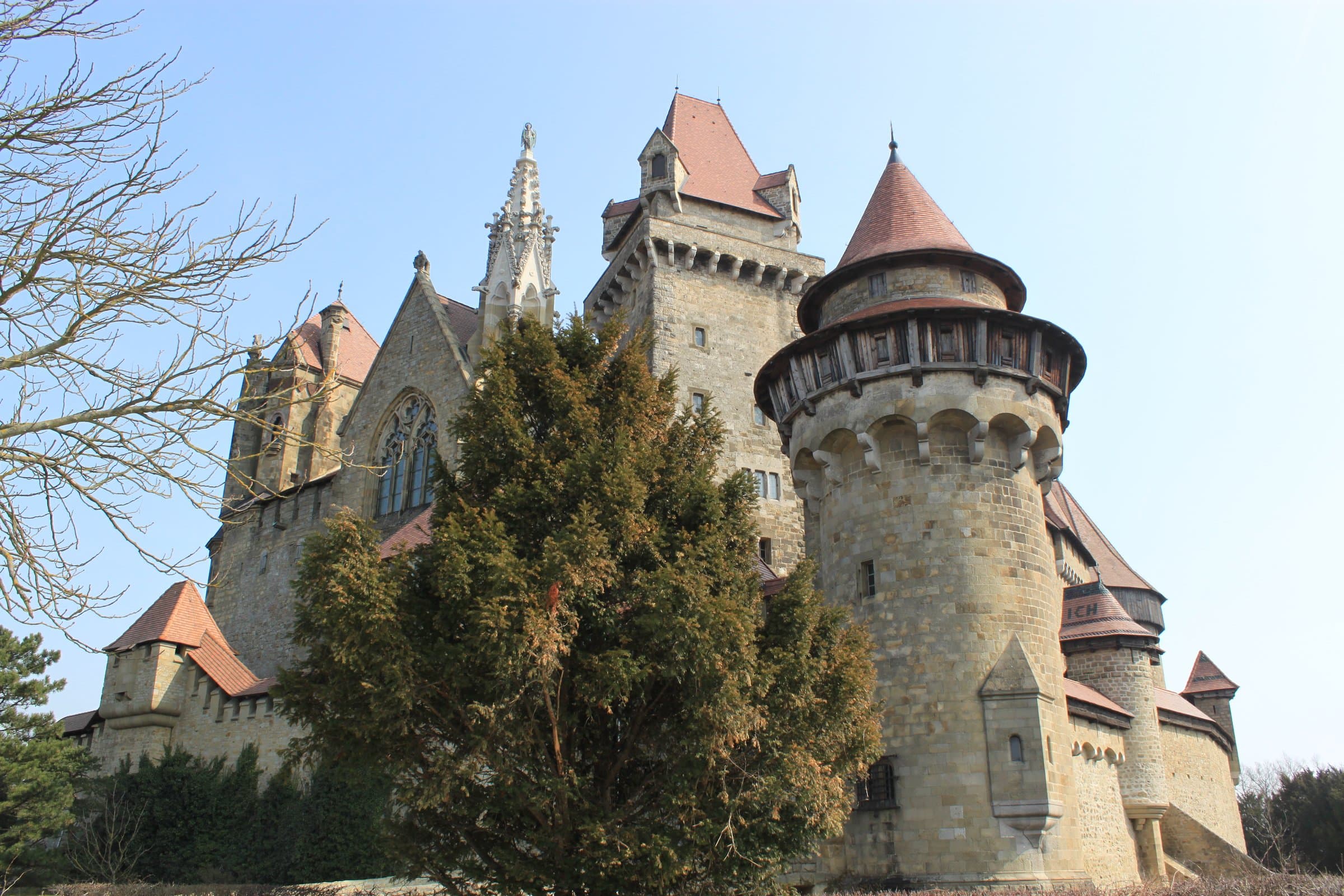Burg Kreuzenstein mit Rundturm und Bäumen vor den Mauern