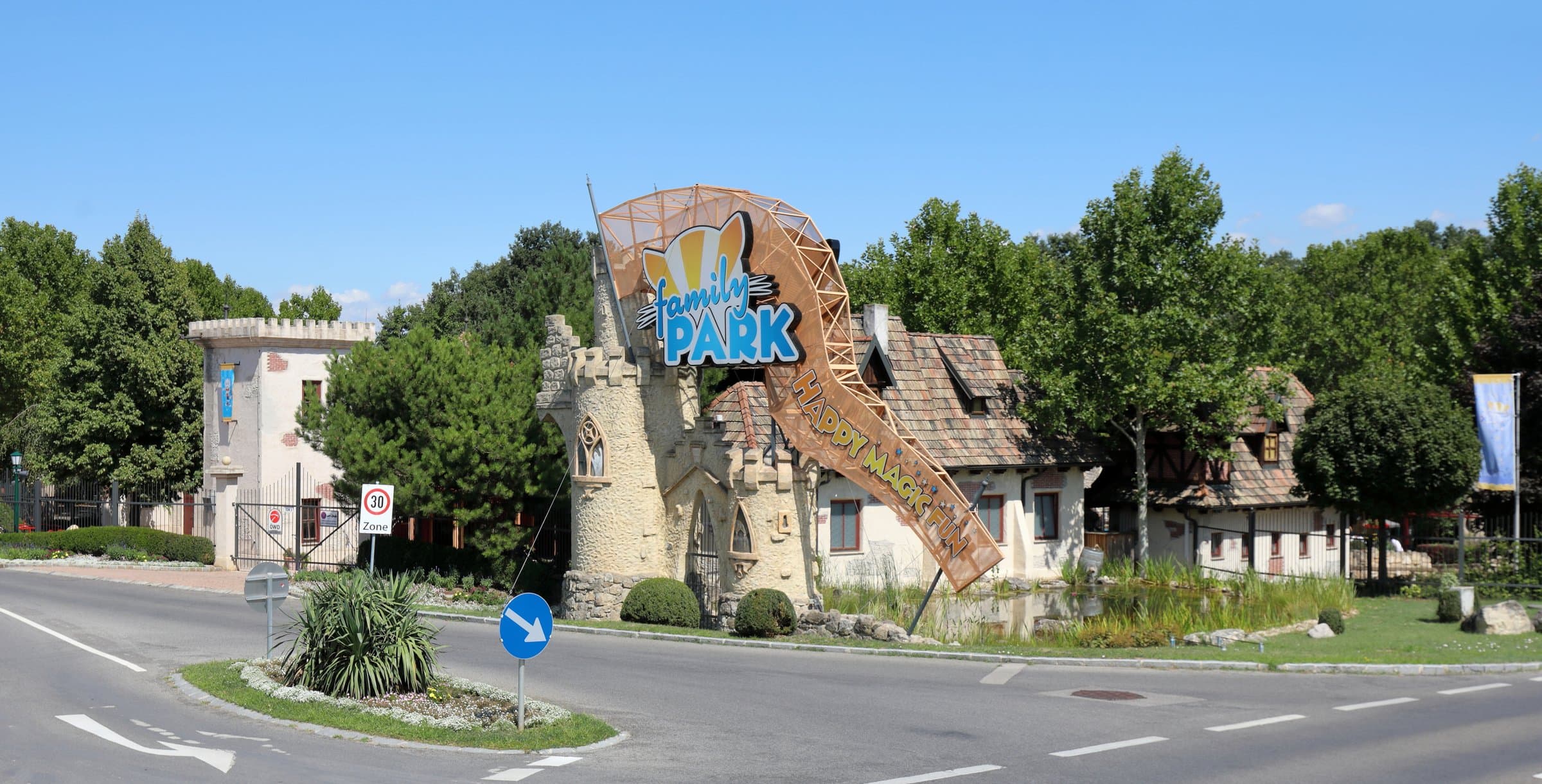 Geschwungener Eingangsbereich des Familyparks mit Logo, Maskottchen und steinernen Türmen