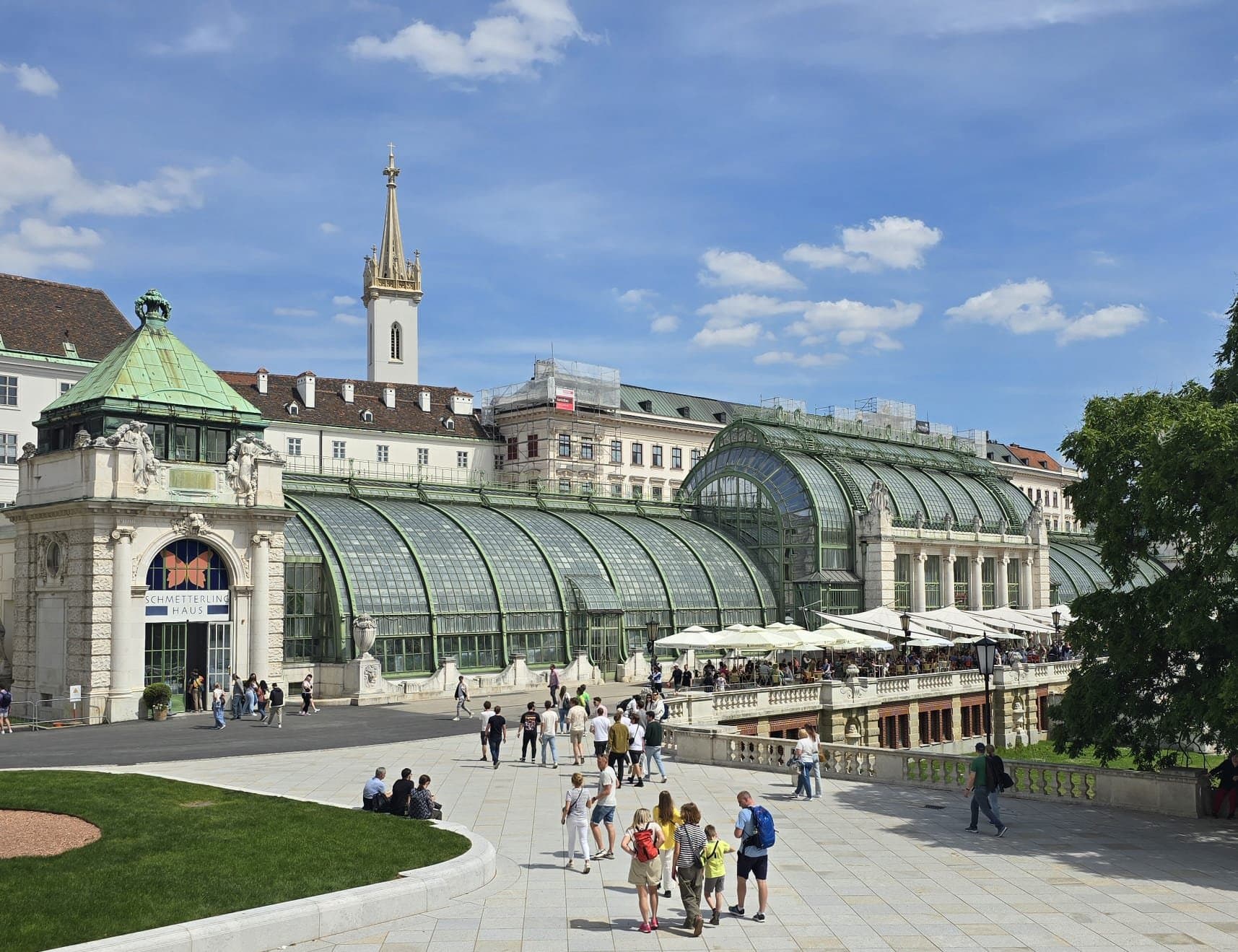 Palmenhaus im Wiener Burggarten mit geschwungener Glasfassade und belebter Terrasse