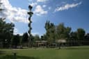 Uhrturm des Gänsehäufels mit Wendeltreppe hinter einer baumbestandenen Liegewiese